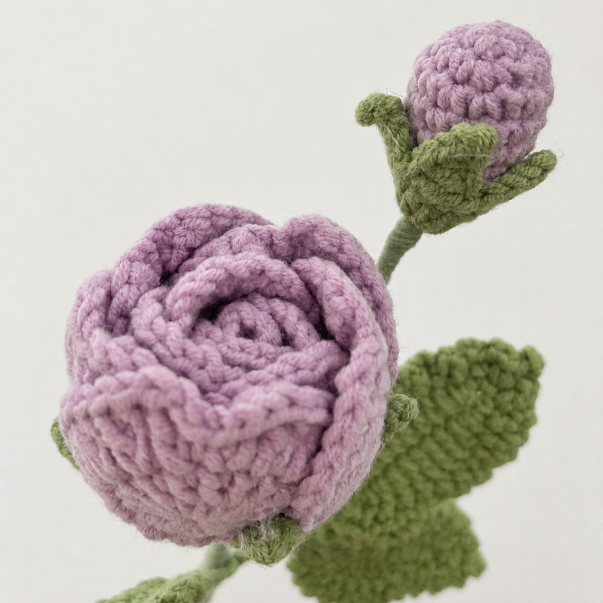 Close-up detail of light purple crochet rose and bud
