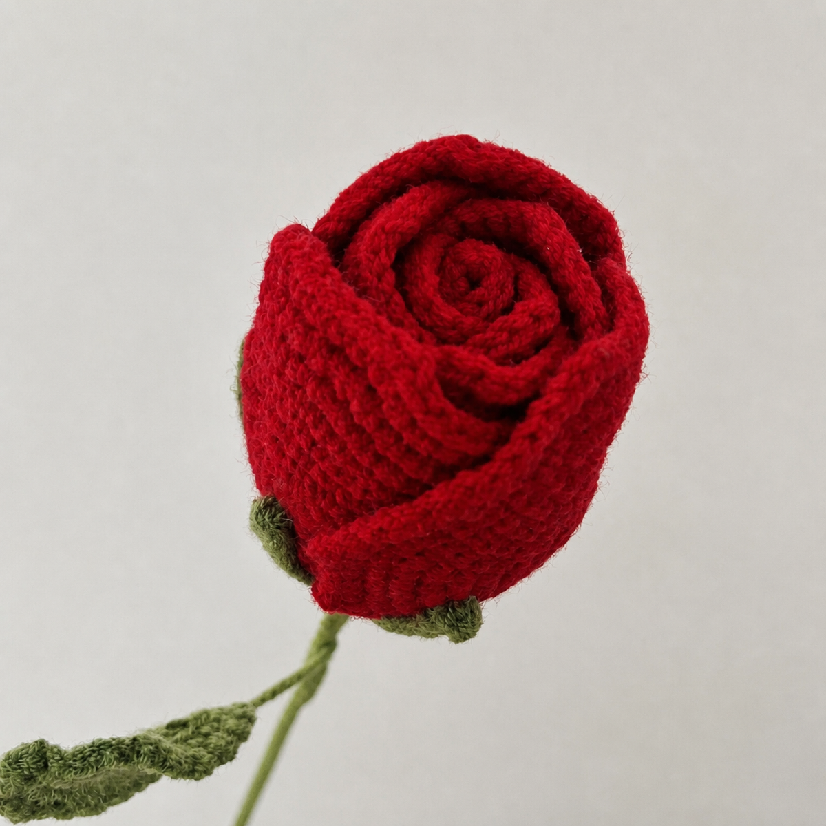 Close-up detail of handmade red crochet rose petals and stitches