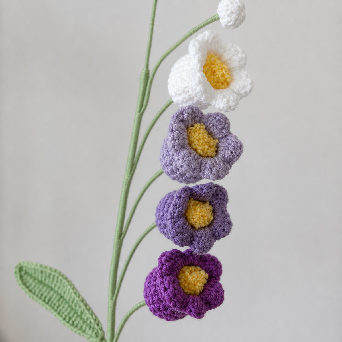 Close-up of four-colour gradient purple crochet bellflowers with yellow centres