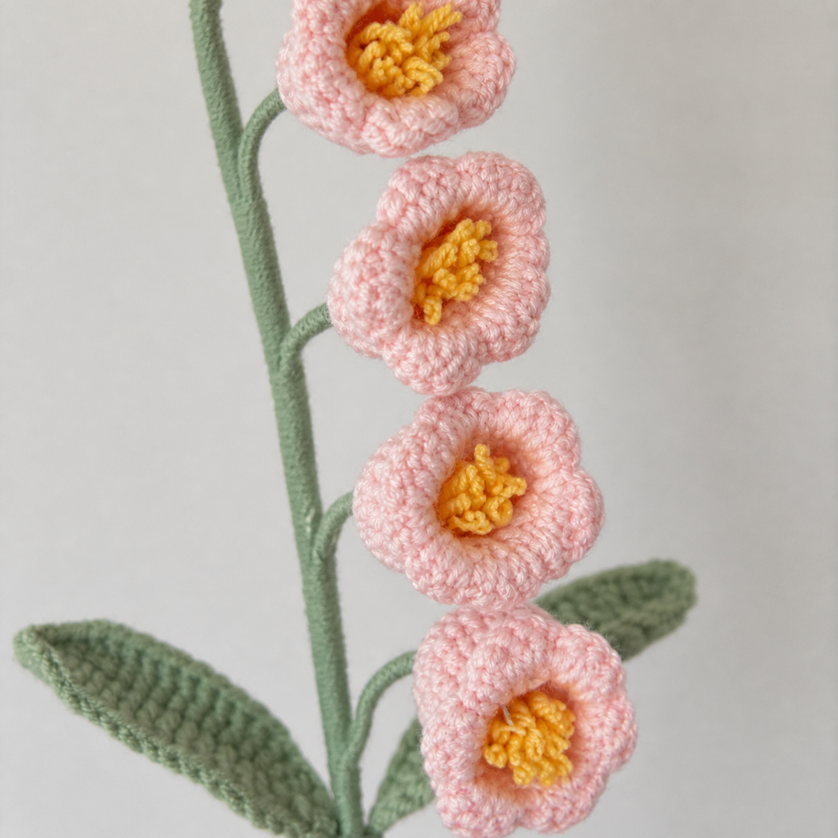 Close-up detail of cherry blossom pink crochet lily of the valley with yellow centers