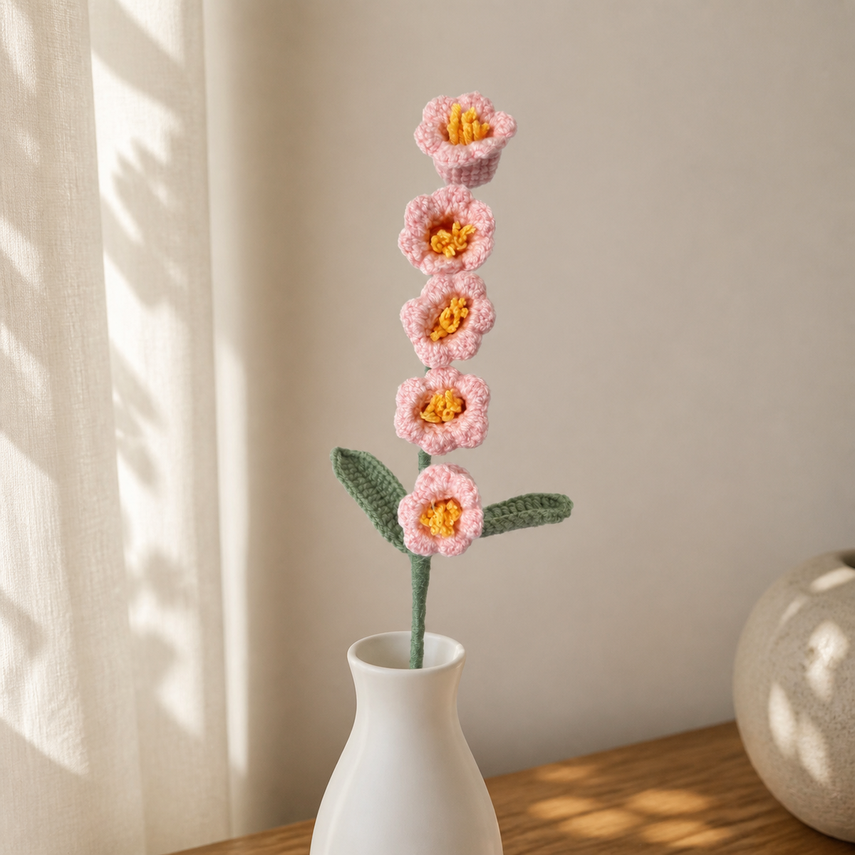Handmade cherry blossom pink crochet lily of the valley displayed in a white vase