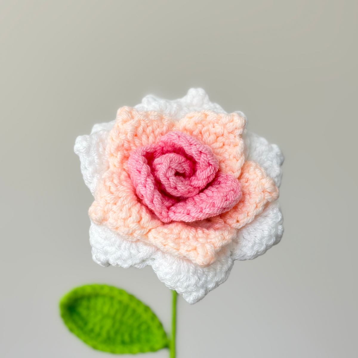 Close-up front detail of handmade pink and white crochet rose