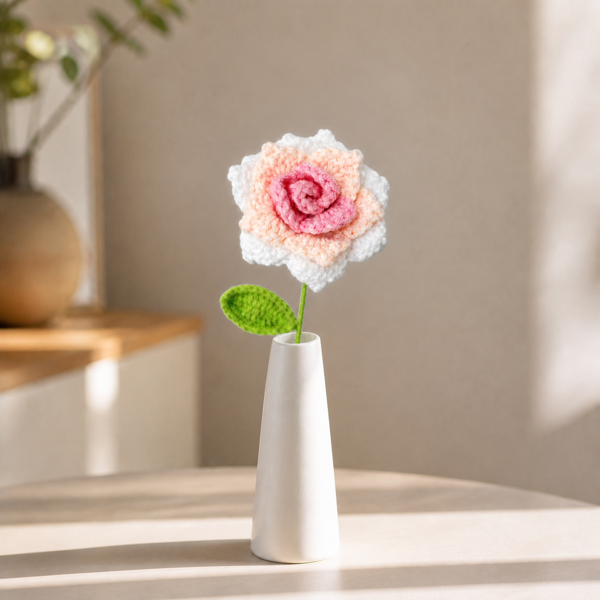 Handmade pink and white crochet rose displayed in a tall white vase