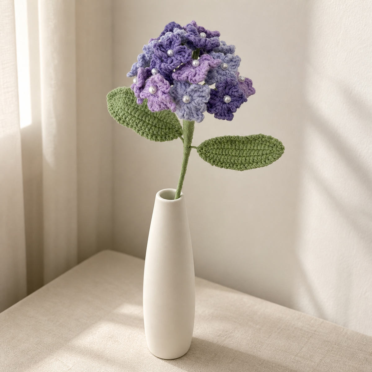 Handmade tricolor purple crochet hydrangea displayed in a tall white vase